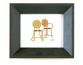 May include: A framed illustration of two chairs with a sunburst design. The chairs are yellow and orange and have a black outline. The illustration is signed "Gil".