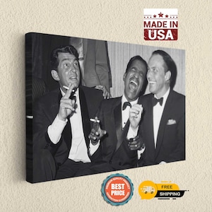 May include: Black and white photograph of three men in suits laughing. The man in the middle is wearing a tuxedo and has his hand on the man on the right's shoulder. The man on the left is holding a cigarette.