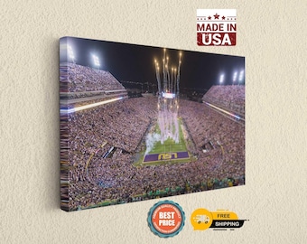 Pode incluir: Uma tela retangular com uma vista aérea noturna de um estádio de futebol lotado. Fogos de artifício explodem sobre o campo, que exibe o logotipo da LSU em roxo e dourado. A impressão inclui o logotipo MADE IN USA no topo.