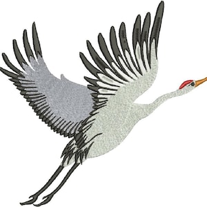 May include: A gray and black crane with its wings spread, flying in mid-air. The crane has a long, thin neck and a red beak.