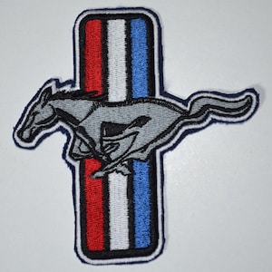May include: An embroidered patch featuring a grey galloping horse silhouette layered over a vertical rectangular emblem with three distinct stripes in red, white, and blue, all outlined with a thick dark blue border and white stitching.