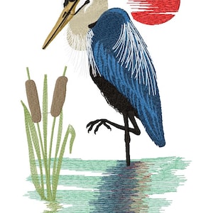 May include: An embroidered design featuring a blue heron standing in water with cattails. The heron has a long yellow beak, white and tan neck, and blue wings. A red sun is in the background, and the water is a mix of blue and green.