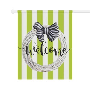 May include: A welcome sign with a white wreath and a black and white bow on a green and white striped background.