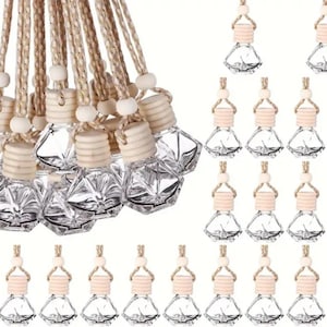 May include: A selection of clear glass car air freshener bottles with wooden caps and beige rope hangers. The bottles have a geometric shape and are arranged in a group, with several others displayed below.