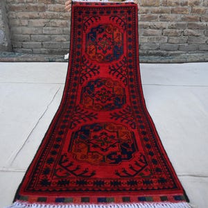 May include: A red runner rug with a traditional Persian design. The rug has a black border and intricate patterns in shades of red, blue, and orange.