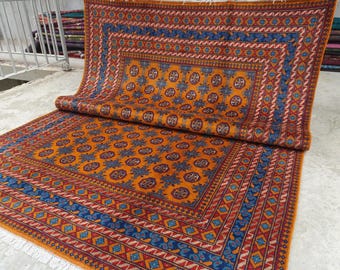 May include: A rectangular area rug featuring a vibrant orange field decorated with repeating blue and dark red circular floral motifs. The rug is framed by multiple intricate borders in shades of blue, red, and orange, finished with white fringe.