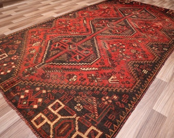 May include: A red and black vintage rug with a geometric pattern. The rug has a worn and faded look, giving it a rustic and antique feel.
