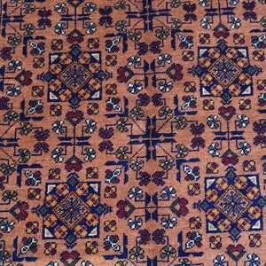 May include: A detailed close-up of a rug with a repeating geometric pattern. The rug features a warm, peach-colored background with a complex design in navy blue, burgundy, and gold. The border is a darker blue with intricate detailing.