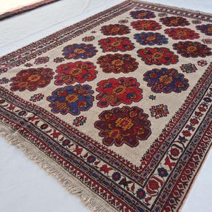 May include: A traditional cream-colored rug with a repeating floral pattern in shades of red, blue, and brown. The rug has a fringe border.