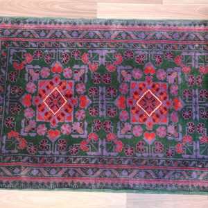 May include: A green, red, and purple patterned rug with a fringe border. The rug is rolled up and has a traditional design.