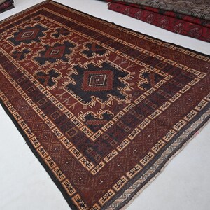 May include: A rectangular, hand-woven rug with a central geometric design in shades of brown, black, and beige. The rug features a detailed border and intricate patterns, showcasing a traditional aesthetic. The rug is suitable for living rooms and bedrooms.
