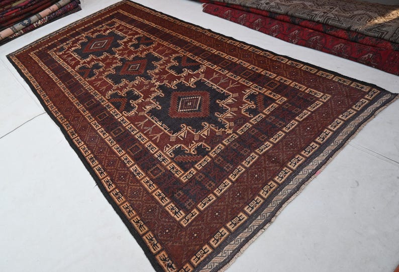 May include: A rectangular, hand-woven rug with a central geometric design in shades of brown, black, and beige. The rug features a detailed border and intricate patterns, showcasing a traditional aesthetic. The rug is suitable for living rooms and bedrooms.
