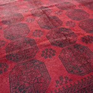 May include: A red rug with a repeating geometric pattern in black. The rug has a central field of red with large octagonal shapes and smaller floral motifs. The border is a darker shade of red with intricate designs.