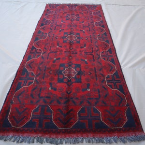 May include: A red and blue rug with a traditional Persian design. The rug has a fringe border and intricate geometric patterns.