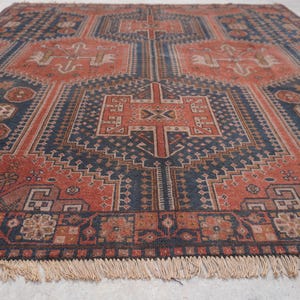 Pu&ograve; includere: Un tappeto antico con un motivo geometrico nei toni blu navy, ruggine e beige. Il tappeto presenta un motivo a medaglione centrale e un bordo con frange. Le dimensioni del tappeto sono di circa 244 cm per 305 cm.