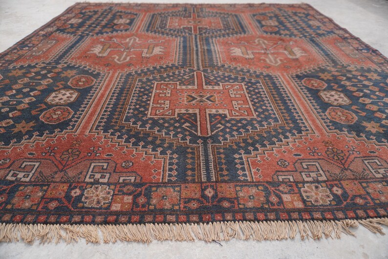 Pu&ograve; includere: Un tappeto antico con un motivo geometrico nei toni blu navy, ruggine e beige. Il tappeto presenta un motivo a medaglione centrale e un bordo con frange. Le dimensioni del tappeto sono di circa 244 cm per 305 cm.