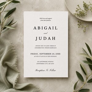 Op de afbeelding: Een rechthoekige witte trouwkaart met zwarte schreefletters die luidt: With love and support from their families, ABIGAIL and JUDAH, INVITE YOU TO JOIN THEM IN CELEBRATING THEIR MARRIAGE, FRIDAY, SEPTEMBER 20, 20XX, AT SIX O'CLOCK IN THE EVENING, 456 ANYWHERE AVENUE, ANYWHERE CITY, AB 12345, Reception To Follow.
