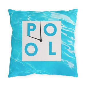 May include: Square throw pillow with a blue water pattern background. The pillow features a white square with the word "POOL" in blue letters and a clock face design. The clock hands point to 4 o'clock.