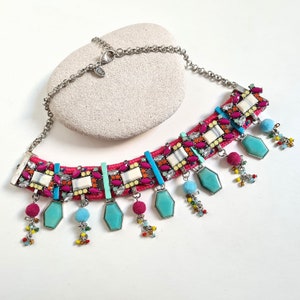 May include: A colourful statement necklace with a pink cord base, turquoise and white geometric beads, and dangling turquoise stones.
