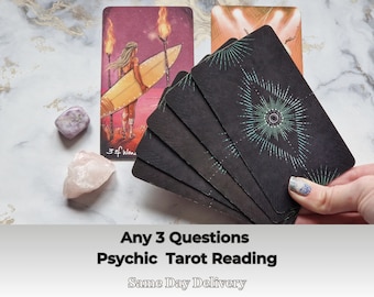 May include: A tarot card reading service offering answers to any three questions. The image shows a hand holding a spread of black tarot cards with a green and blue design. The text "Any 3 Questions Psychic Tarot Reading Same Day Delivery" is visible at the bottom of the image.