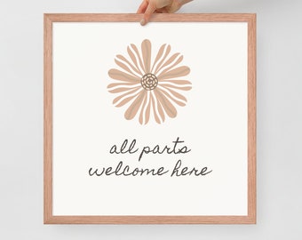 May include: A square framed print with a light wood frame featuring a beige line-art flower illustration centered above the black cursive text "all parts welcome here" on a white background, presented in a clean and simple composition.