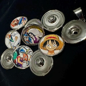 Puede incluir: Un conjunto de ocho botones a presión plateados con imágenes coloridas de personajes de anime. Las imágenes incluyen un hombre con un sombrero de paja, una mujer con el pelo largo y negro y un hombre con una bata blanca.