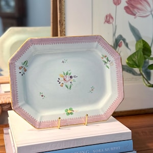 May include: An octagonal, light blue serving platter with a pink border and gold trim. The platter features a floral design in the center and is displayed on a gold stand atop a stack of books. The books are titled "Shades of Country", "Country House Living", and "Country House Style".