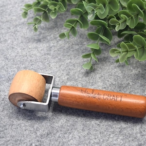 May include: A wooden roller with a metal frame and a wooden handle. The handle is engraved with the text "Simple Craft".