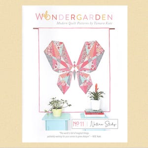 May include: A quilt pattern featuring a pink and blue butterfly with geometric shapes. The pattern is titled "Wondergarden No. 11 Nature Study" and is by Tamara Kate.