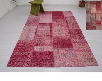 Könnte beinhalten: Ein großer, rechteckiger Patchwork-Teppich in Rosa- und Rottönen. Der Teppich weist eine Vielzahl von Mustern und Texturen auf und hat einen Used-Look. Im Hintergrund befindet sich ein kleiner grüner Hocker.