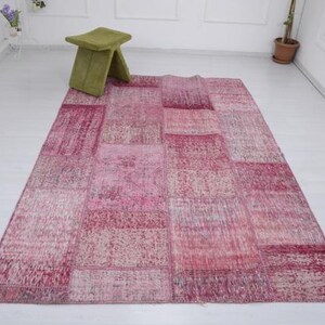 May include: A pink patchwork rug with a variety of textures and patterns. The rug is made from recycled materials and is perfect for adding a touch of bohemian style to any room.