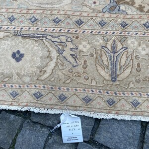 May include: A beige hand-woven rug with a floral pattern in shades of blue, brown, and pink. The rug has a fringe border and a tag that reads "Stock No. 46,962, 192 x 280, 5.73 m2, Hand Made, Made in Turkey."