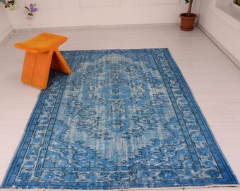 Puede incluir: Una alfombra vintage azul y blanca con un patrón floral. La alfombra tiene un aspecto desgastado y es perfecta para agregar un toque de estilo bohemio a cualquier habitación.