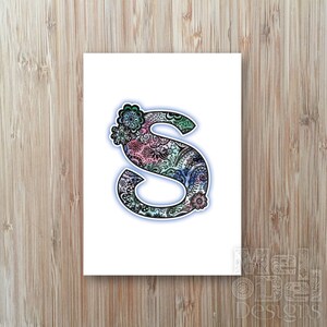 May include: A white card featuring a decorative letter "S" with a floral design. The letter is filled with intricate patterns in shades of pink, blue, and green, outlined in black with a blue glow.