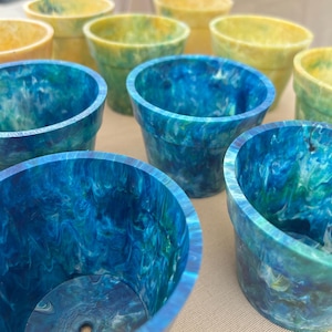 May include: A collection of colourful, swirl-patterned plastic plant pots. The pots are in shades of blue and yellow.