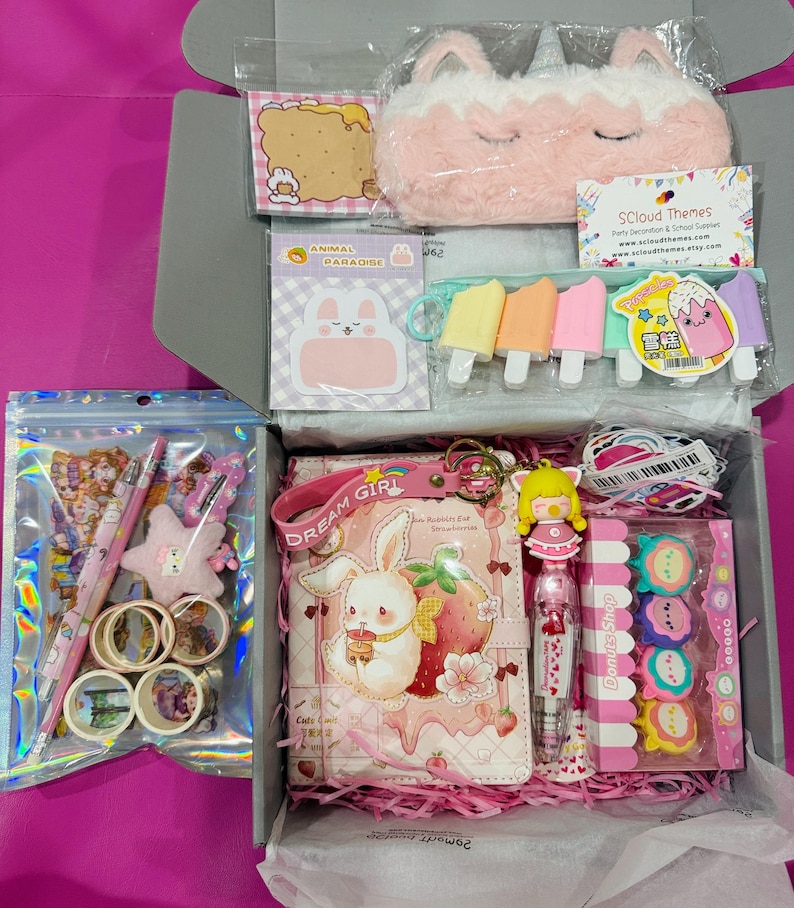 Op de afbeelding: Een briefpapier-cadeaubox met een pluche eenhoorn-etui, een notitieboek met een konijn- en aardbeienafbeelding, een pen met een poppenbedel, ijsvormige gummen, donutvormige gummen, washi-tape rollen, stickers en een memoblok.