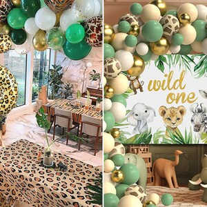 May include: A jungle-themed party decoration set with green, gold, and cream balloons, a leopard print number one balloon, and a sign that says "wild one".