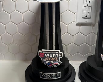 Könnte beinhalten: Eine Trophäe mit einem silbernen Cowboyhut auf einem schwarzen Ständer mit drei vertikalen Stützen. Eine Plakette zeigt WURTH 400 TEXAS MOTOR SPEEDWAY LIQUI MOLY, eine untere Plakette WINNER MAY 3, 2026. Der runde schwarze Sockel ist mit Sternen verziert.
