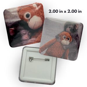 May include: Square button pins, each 2.00 inches by 2.00 inches, featuring images of monkeys and a stuffed animal. One pin shows a sleeping monkey with a teddy bear, and another shows a monkey hugging a stuffed monkey. The back of one pin is visible.