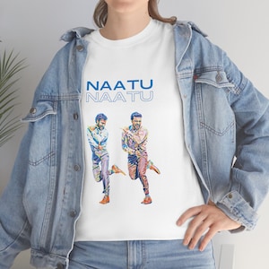 May include: White t-shirt with a blue and white graphic of two men dancing. The text "NAATU NAATU" is printed in blue above the graphic.