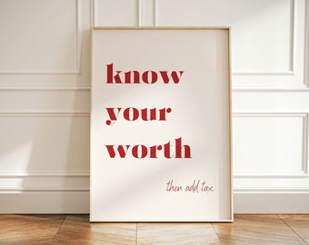 May include: A framed print with the words "know your worth" in red, with "then add tax" below. The print is leaning against a white wall with molding, on a wooden floor.