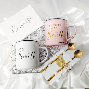 Our beautiful Engagement Gift Box, featuring a set of 2 Stoneware enamel look Mugs, 2 golden coffee spoons, and a heartfelt Congrats card with your personal message on it in a gift box with satin ribbon and gift tag.  A perfect Engagement gifts.