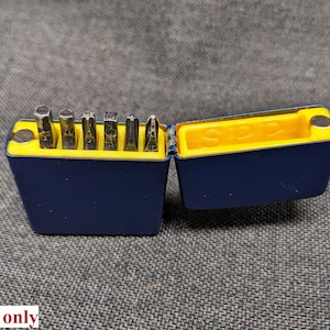 May include: A blue and yellow tool case with a magnetic closure, open to reveal a set of eight different sized screwdriver bits.