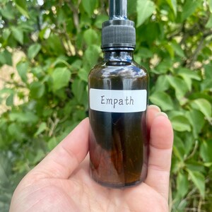 May include: A brown glass bottle with a dropper top and a white label that says "Empath".