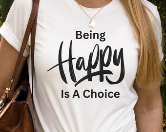 May include: White t-shirt with black text that reads "Being Happy Is A Choice".
