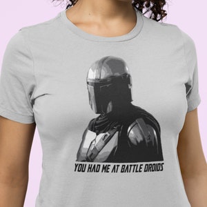 May include: A gray t-shirt with a black and white image of a Mandalorian character. The text "You had me at battle droids" is printed below the image.