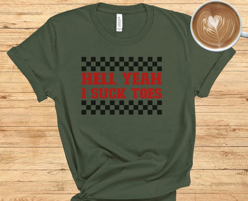 Puede incluir: Una camiseta verde con un patr&oacute;n de cuadros blanco y negro y el texto "Hell Yeah I Suck Toes" en rojo.