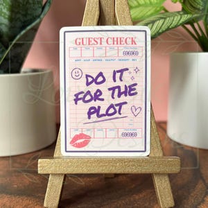 May include: A sticker resembling a guest check, featuring the text "DO IT FOR THE PLOT" in purple. The design includes a smiling face, stars, a heart, and a kiss mark. The check number is 696969.
