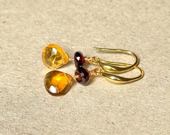 Puede incluir: Pendientes de oro con una piedra preciosa naranja en forma de lágrima y una piedra preciosa roja redonda.