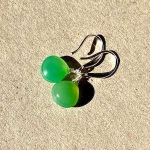 May include: A pair of silver dangle earrings with green gemstone drops.